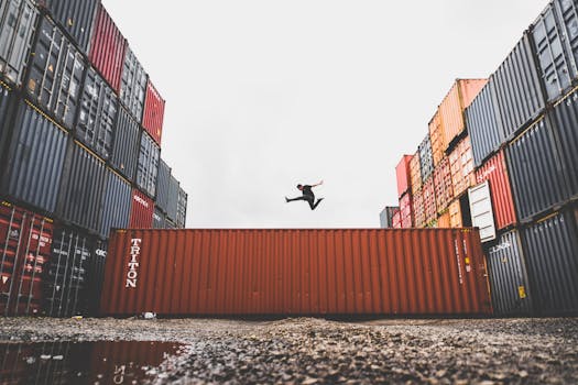 A person leaps dramatically above stacked shipping containers, showcasing freedom and industrial energy.